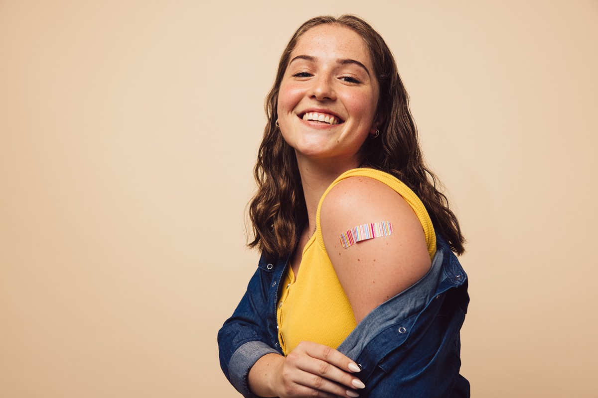 Young adult female posing with band-aid from immunization